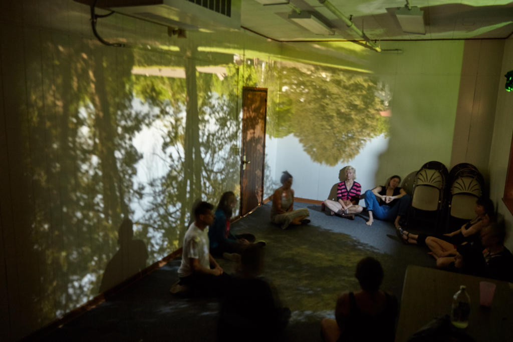Students participating in sonic meditation in during an experimental music class sitting in a classroom-sized camera obscura made by another class. Photo by Suzi Sadler